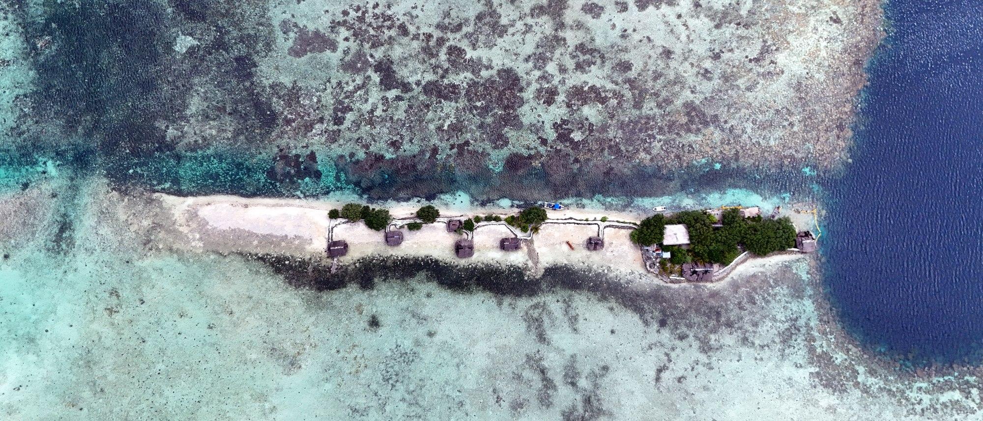 空から見たダウンレレ——白砂の細い島とヤシ葺きの小屋、周囲に広がるリーフ