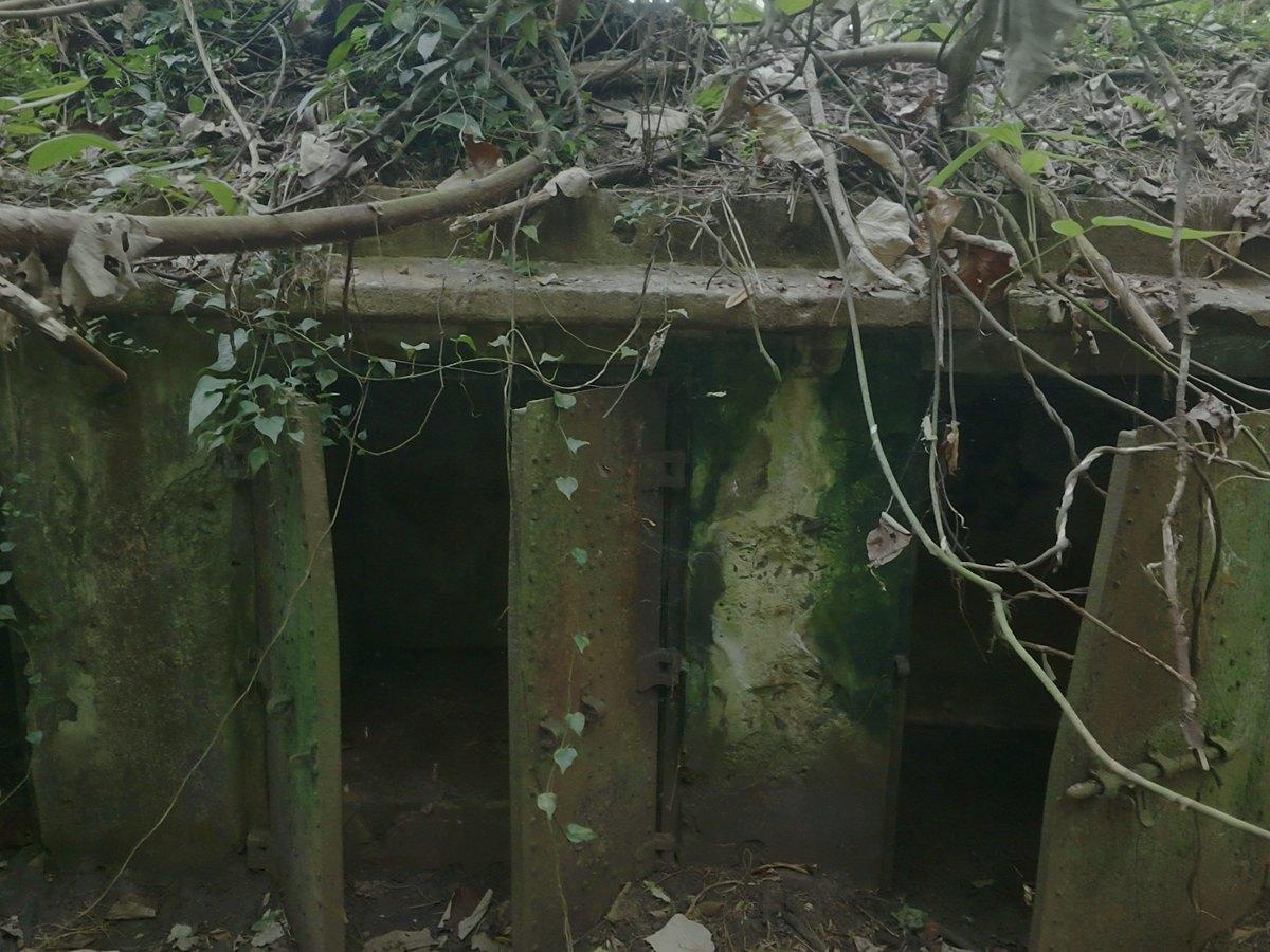 A concrete ammunition magazine with rusted steel doors still hanging