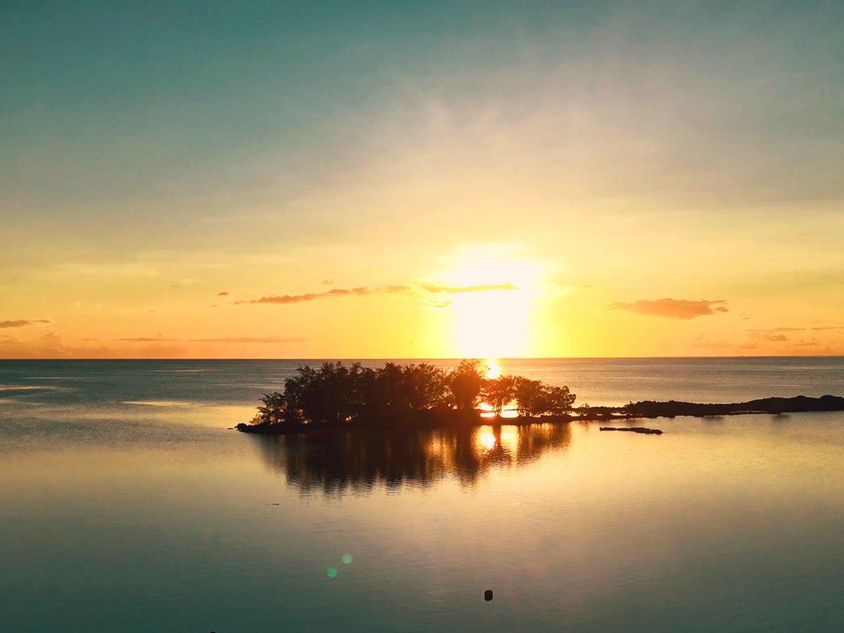 A small islet in the lagoon, sunset reflected on the water