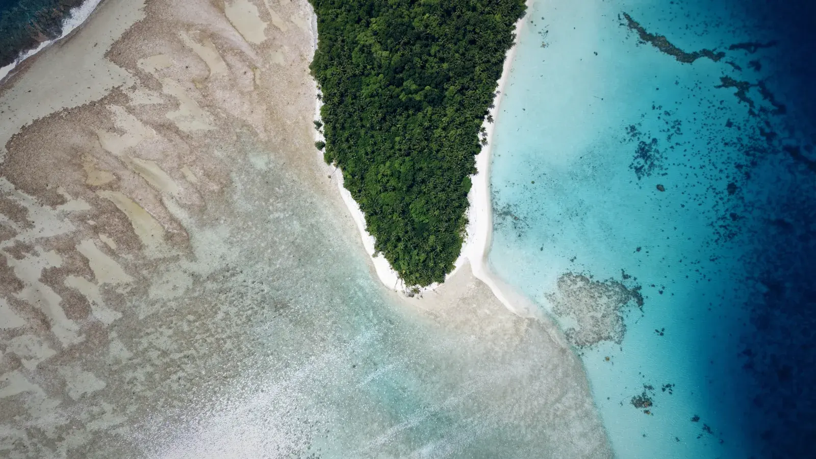 A deserted islet with a white-sand spit and turquoise reef